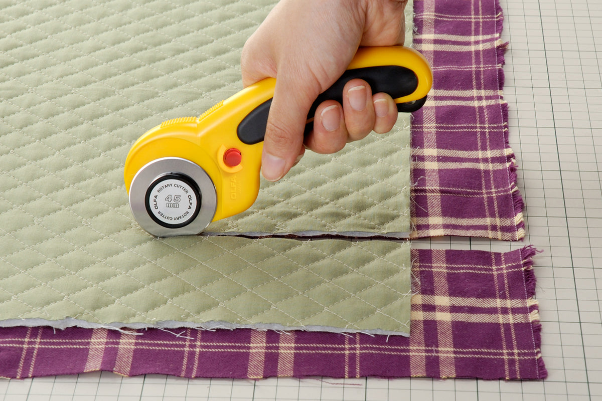Photo of OLFA Deluxe Ergonomic Rotary Cutter 45mm (OLF/RTY2DX) with a curved ergonomic handle, rubber grip, and safety trigger mechanism.