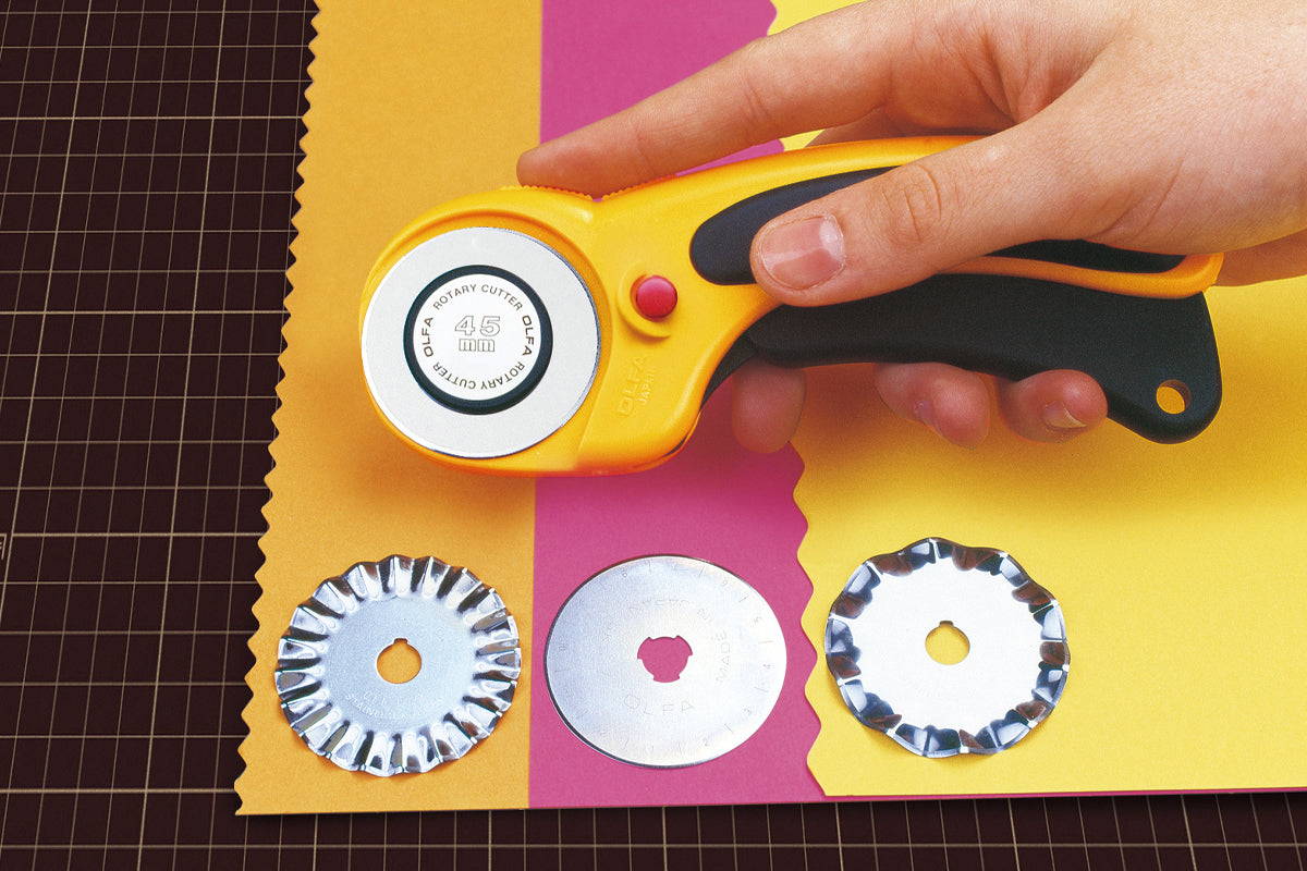 Photo of OLFA Deluxe Ergonomic Rotary Cutter 45mm (OLF/RTY2DX) with a curved ergonomic handle, rubber grip, and safety trigger mechanism.