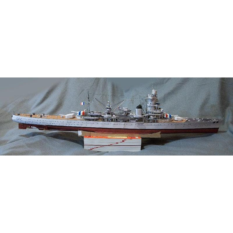 A detailed model of a French battleship displayed on a wooden stand against a gray fabric backdrop.