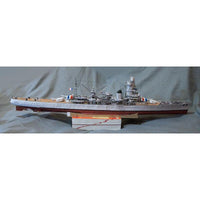 A detailed model of a French battleship displayed on a wooden stand against a gray fabric backdrop.