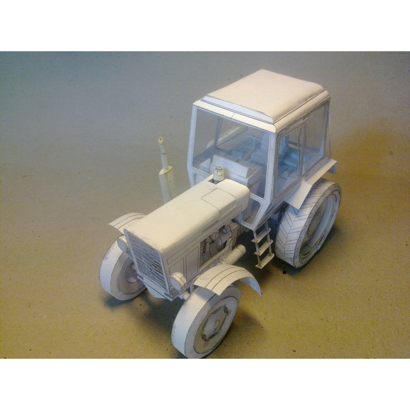 An unpainted white model tractor, likely an RC car or miniature, shown from a three-quarters angle on a neutral gray gradient background.