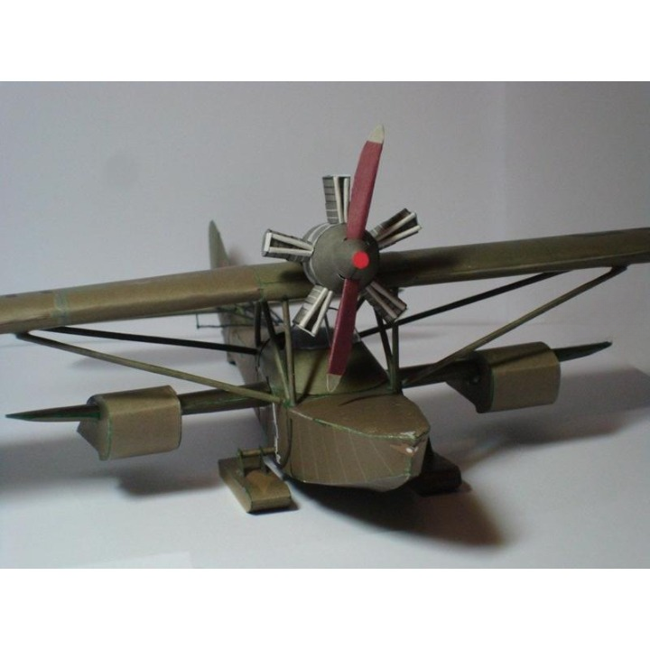 A vintage-style biplane model aircraft with olive drab and brown painted fuselage, wings, and engine cowling, featuring a red and silver propeller, photographed on a plain light background.