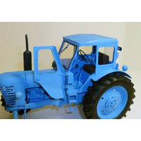 A light blue plastic model tractor with black tires and a black exhaust pipe, shown against a plain off-white background.