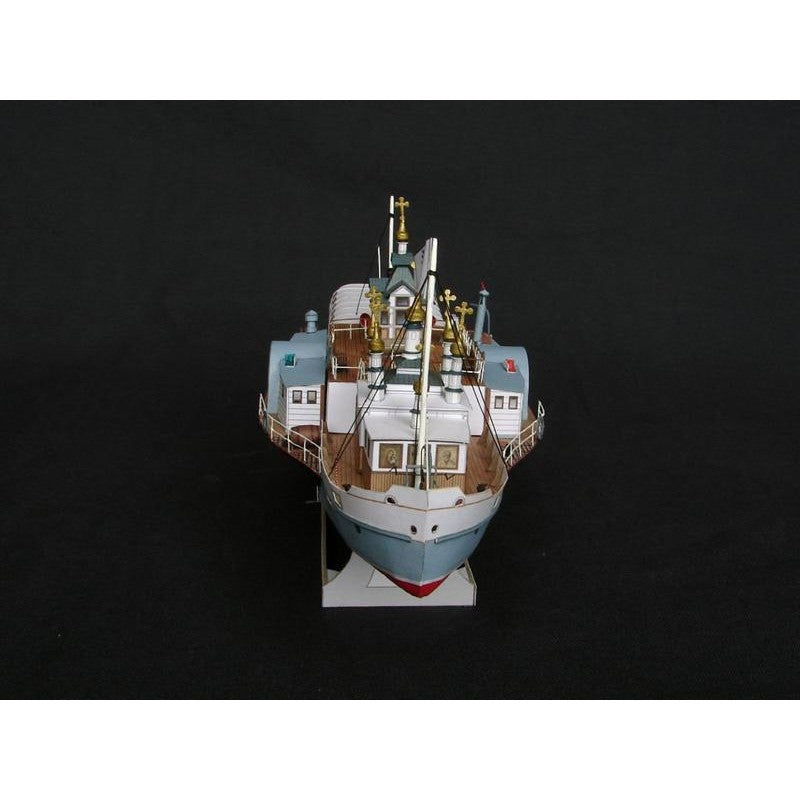 A detailed model of a cargo ship, photographed from a high angle against a solid black background.