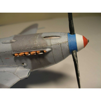 Close-up of a model airplane nose section with a silver fuselage, blue and red nose cone, and black propeller blades.