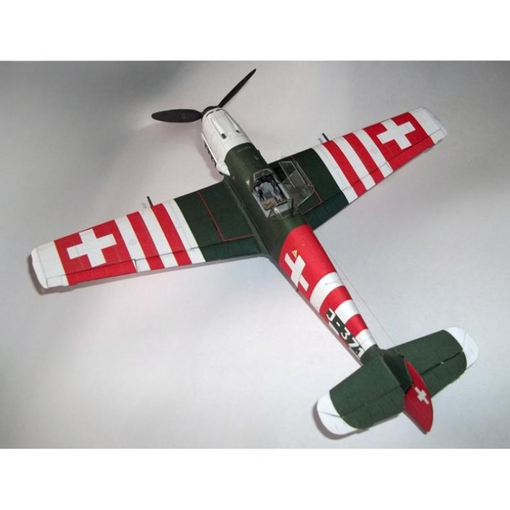 A model of a World War II Swiss fighter plane, likely a Messerschmitt Bf 109, featuring a green and white paint scheme with red and white Swiss cross markings on the wings and tail.