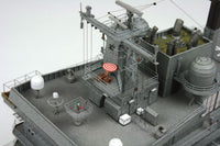 A detailed model of a gray military ship deck, featuring various antennas, radar domes, communication equipment, and small crew stations, photographed against a plain light gray background.