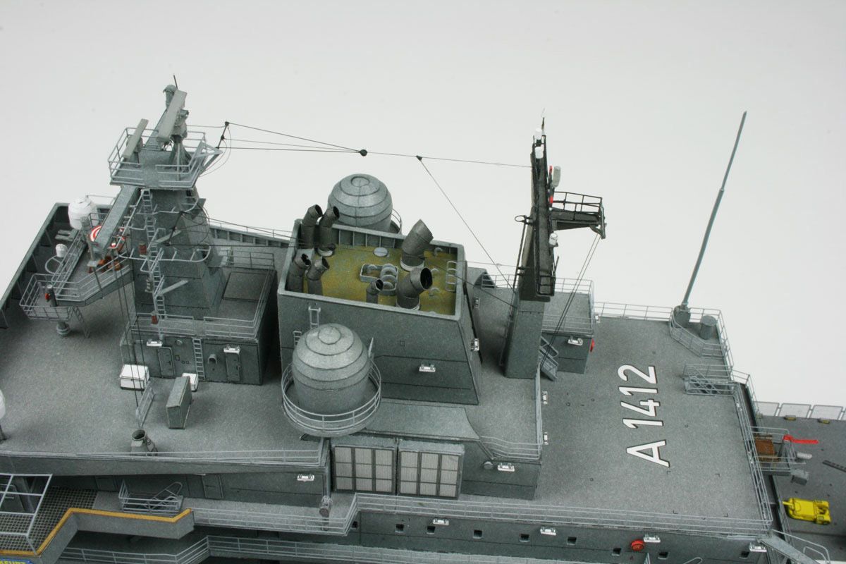 A detailed model of a gray military aircraft carrier deck, featuring radar domes, antennas, and the aircraft landing gear marked with the number A1412, set against a plain light gray background.