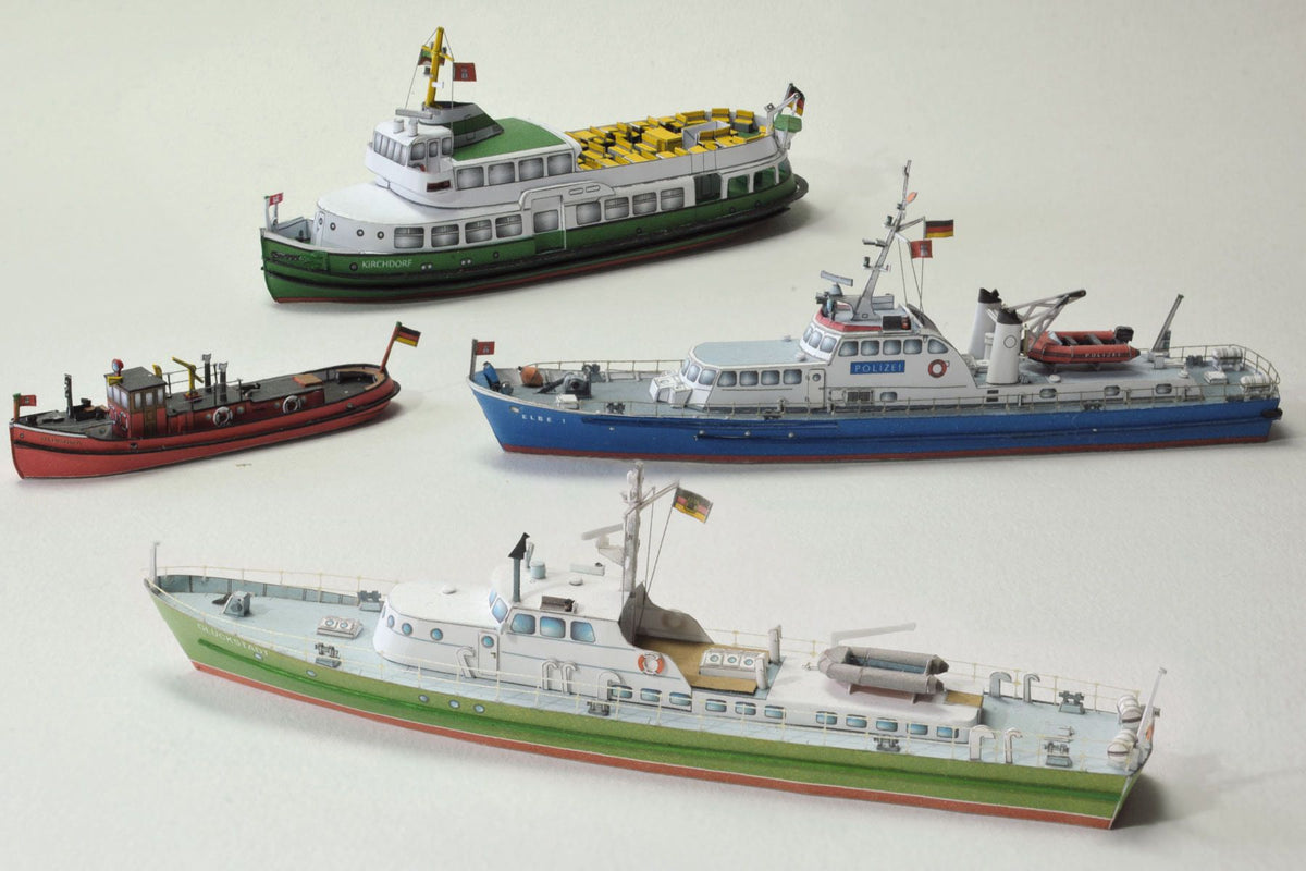 Photo of HMV Hamburg Museum Ships Card Model Kit 103342 showing four detailed paper ship models – Feuerwehr IV, Kirchdorf, Glückstadt, and Elbe 1 – in 1/250 scale