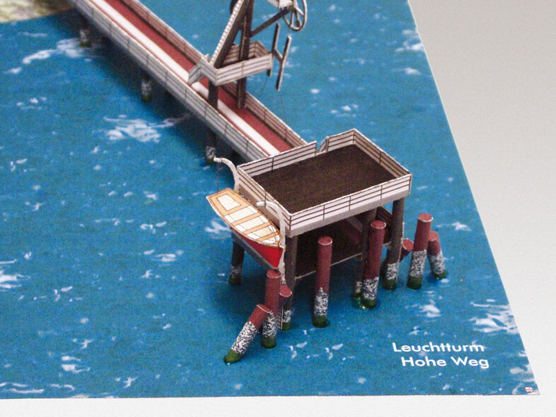 Photo of HMV Hohe Weg Aussenweser Lighthouse 1:250 card model kit showing detailed paper parts, wind semaphore, and water base.