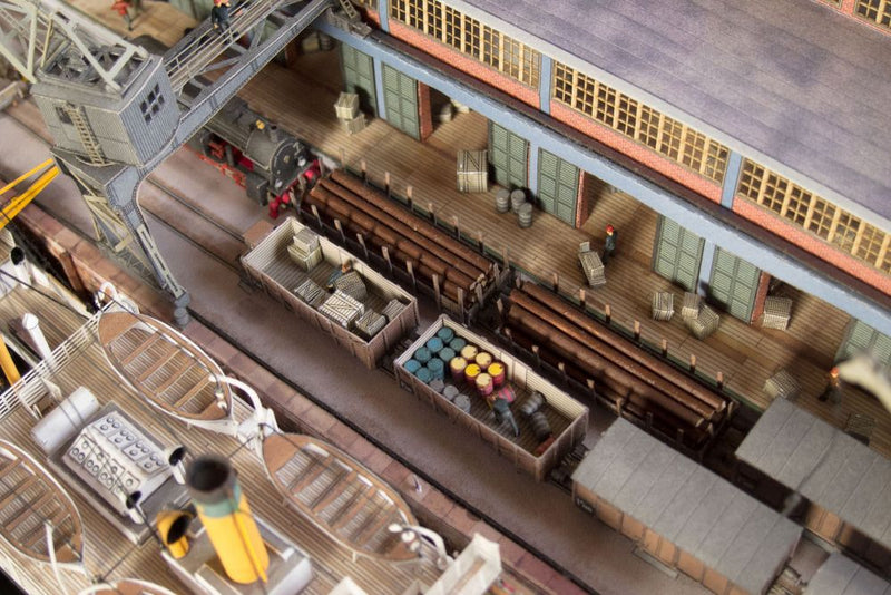 Photo of Harbor Diorama Hamburg 1:250 card model kit by HMV showing the weathered steamer Schwan and detailed 1930s harbor scene with cranes, vehicles, and warehouse.