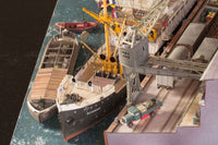 Photo of Harbor Diorama Hamburg 1:250 card model kit by HMV showing the weathered steamer Schwan and detailed 1930s harbor scene with cranes, vehicles, and warehouse.