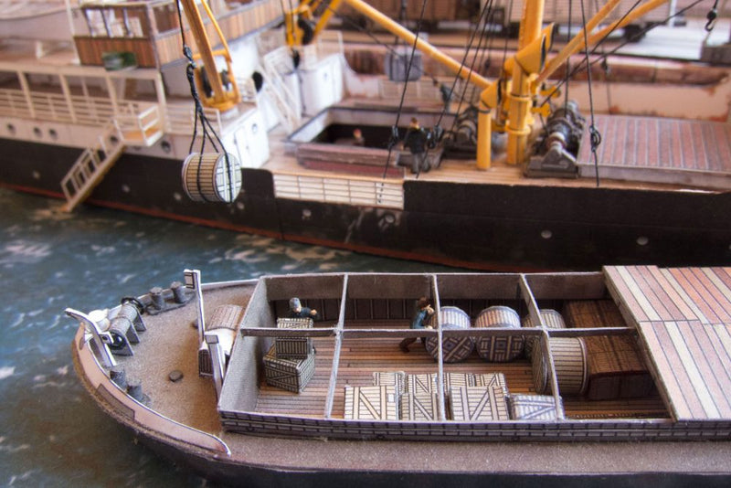 Photo of Harbor Diorama Hamburg 1:250 card model kit by HMV showing the weathered steamer Schwan and detailed 1930s harbor scene with cranes, vehicles, and warehouse.