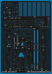 A sheet of blue plastic model kit parts on a black backing, labeled with part numbers and markings for Steve Irwin from 2/11 scale. The sheet includes various small molded components such as grids, panels, and structural pieces.