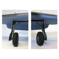 A side-by-side comparison of a model airplane's front landing gear, showing two views of the wheel and strut assembly under a blue-gray wing on a white background.
