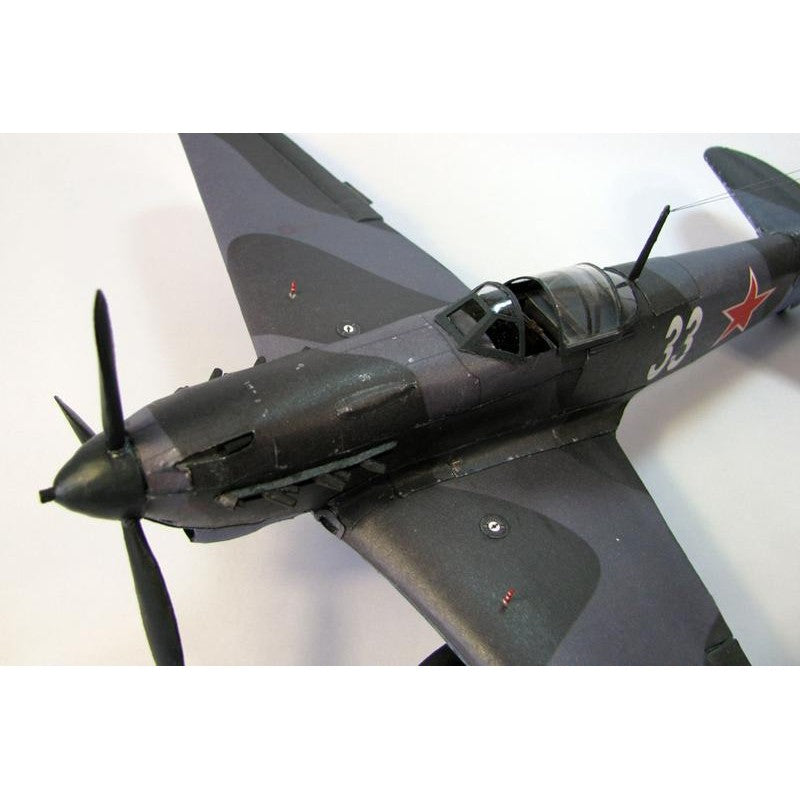 A detailed model of a vintage military fighter plane, painted in a dark gray and black camouflage pattern with a red star and white number '23' on the side, photographed against a plain white background.