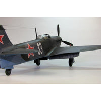 A scale model of a Soviet military jet aircraft, likely a MiG-15, painted in a dark gray camouflage with red star insignias and the number 33 on the fuselage.