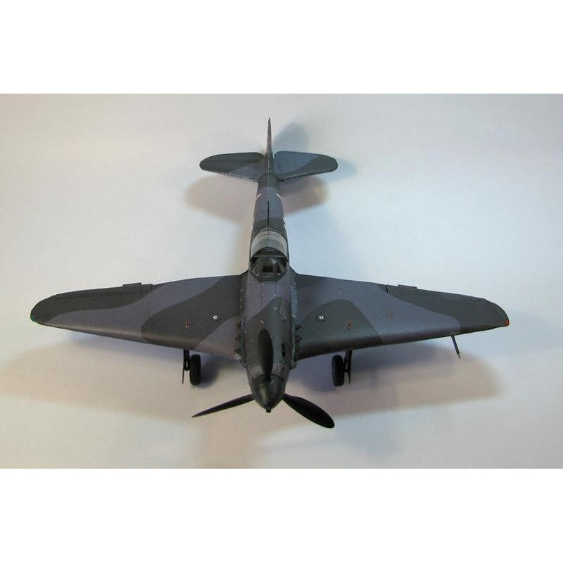 A detailed model of a classic military fighter plane, photographed from a top-down perspective against a neutral light gray background.