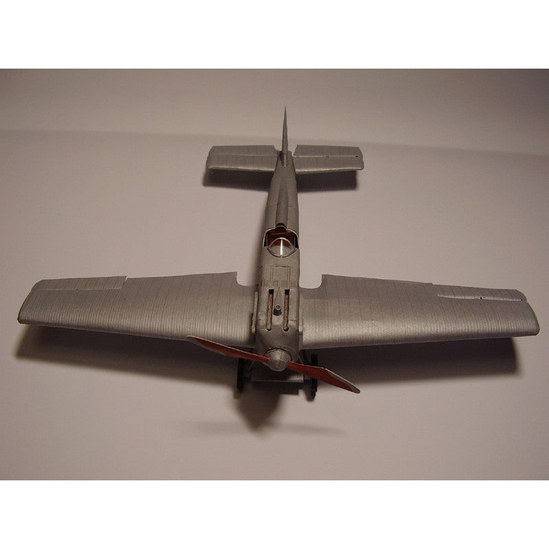 A silver model airplane photographed from above on a plain light background.
