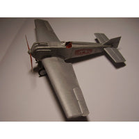 A silver model airplane with red lettering on the side, photographed on a plain light gray background.