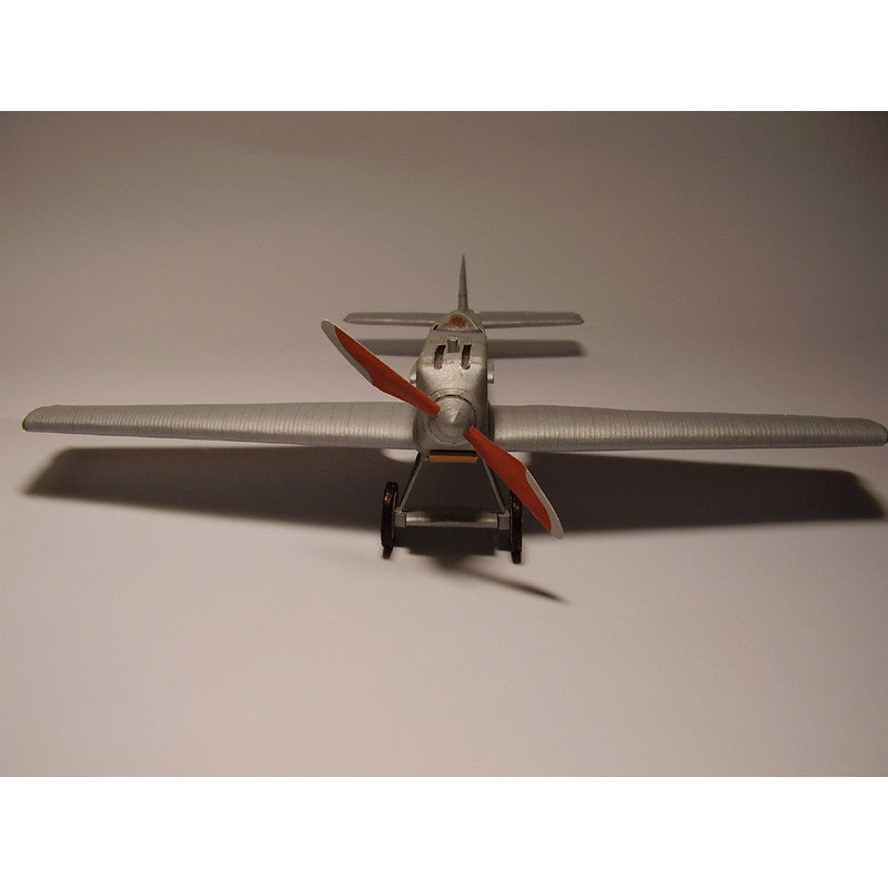 A model silver airplane with red propeller blades, shown from a rear three-quarter view against a plain gray background.