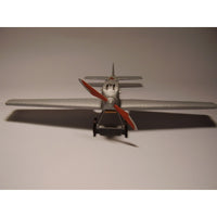 A model silver airplane with red propeller blades, shown from a rear three-quarter view against a plain gray background.