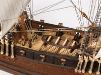 Photo of OcCre Buccaneer Pirate Ship 1:100 Wooden Model Kit fully assembled, showing detailed sails, wooden hull, and rigging.