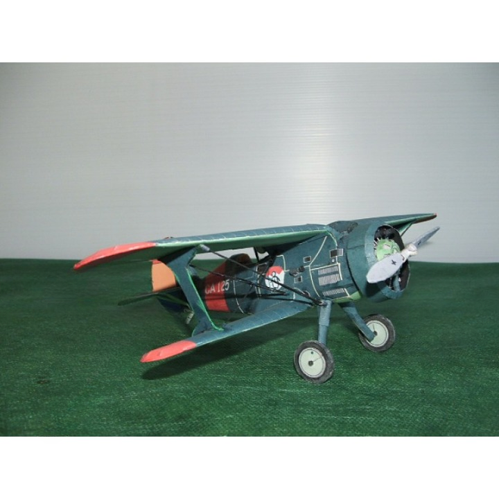 A vintage-style model airplane with a distressed teal-green fuselage, red wingtips, and a white propeller, displayed on a green textured surface against a light gray background.