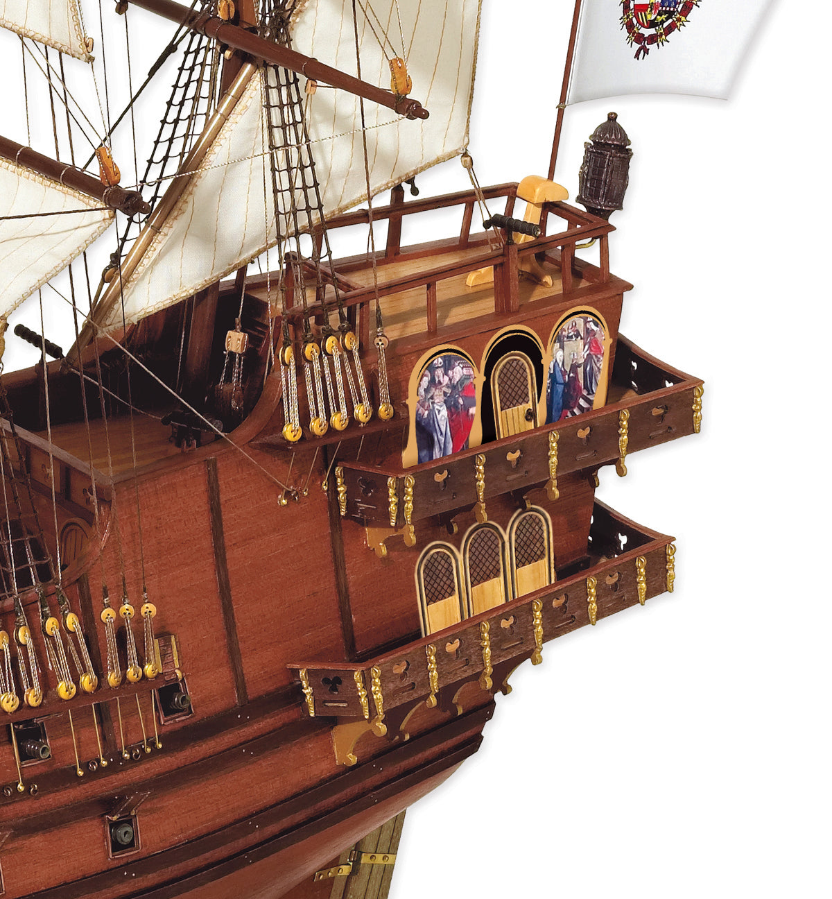 A close-up of a detailed wooden pirate ship model, showing the dark brown hull, white sails, gold accents, and colorful painted windows against a plain white background.