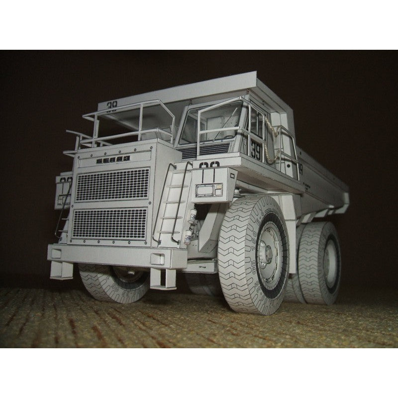 A detailed miniature model of a heavy-duty dump truck, likely for scale modeling, shown against a dark brown background.