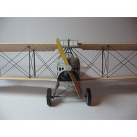 A vintage-style biplane model or toy airplane with a silver and black fuselage, yellow propeller blade, and light wood-toned wings, shown against a plain light gray background.