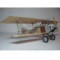 A vintage-style biplane model or miniature aircraft shown in side profile against a plain light gray studio background. The plane has a cream/beige wing structure, dark struts, a white fuselage with black details, a brown side panel, and small roundel markings on the wings.
