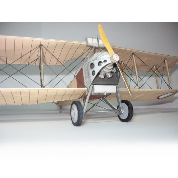 A vintage-style biplane model with a silver fuselage, cream-colored wooden wings, black wire struts, gray wheels, and a yellow propeller, photographed against a plain light gray background.