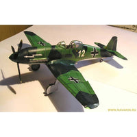 A scale model of a green and black German WWII fighter plane, featuring white German Iron Cross markings and the number '12' on its fuselage, displayed on a white surface.