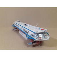 A vintage toy model of a passenger liner, resembling the RMS Titanic, displayed on a beige background. The model is primarily white with blue and red stripes, detailed windows, and a silver metallic bridge.