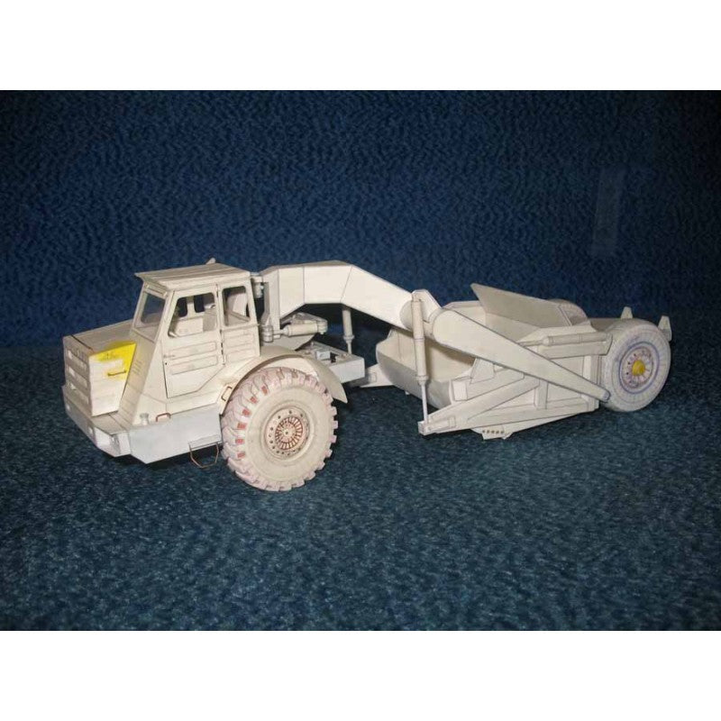 An unpainted miniature model of a heavy-duty crawler loader or excavator, shown in light gray plastic against a dark blue textured background.