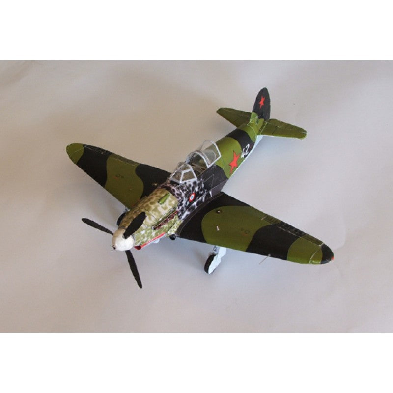 A model of a vintage military fighter plane, likely a Spitfire, featuring a green and black camouflage pattern with red star insignias on the tail, photographed on a plain light background.