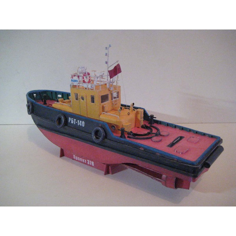 A vintage model toy tugboat, likely a die-cast metal model, shown on a display stand against a plain light background. The boat features a yellow cabin, a dark blue/black hull, and a red deck and lower hull.