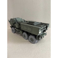 A detailed model of an olive green military truck with a missile launcher on a light beige textured surface.