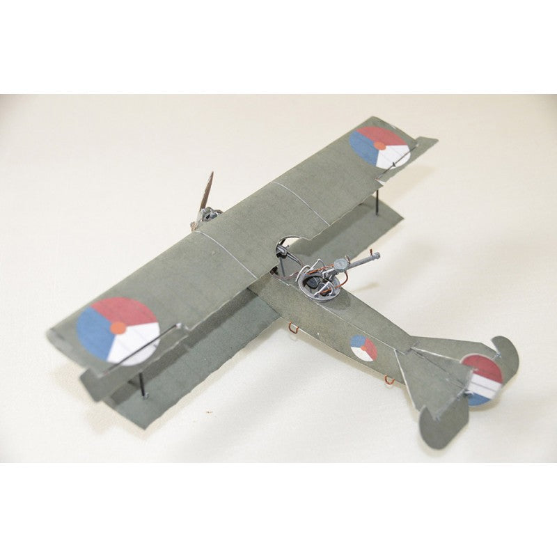 A small model biplane in matte gray with roundel markings in red, white, and blue, photographed on a plain light background.