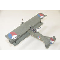 A small model biplane in matte gray with roundel markings in red, white, and blue, photographed on a plain light background.