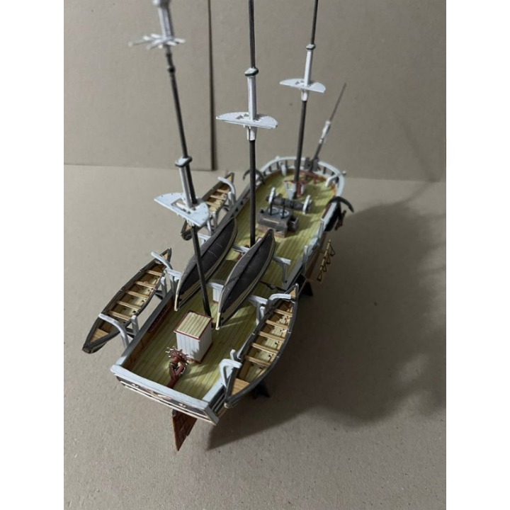 A detailed miniature model of a historical sailing ship, shown from an elevated rear-three-quarter angle on a plain beige background.
