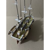 A detailed miniature model of a historical sailing ship, shown from an elevated rear-three-quarter angle on a plain beige background.