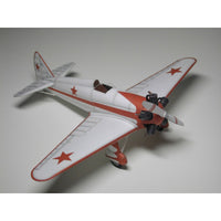 A model of a vintage Soviet fighter plane, featuring a white fuselage and wings with red stripes and red star insignias, photographed on a neutral gray background.