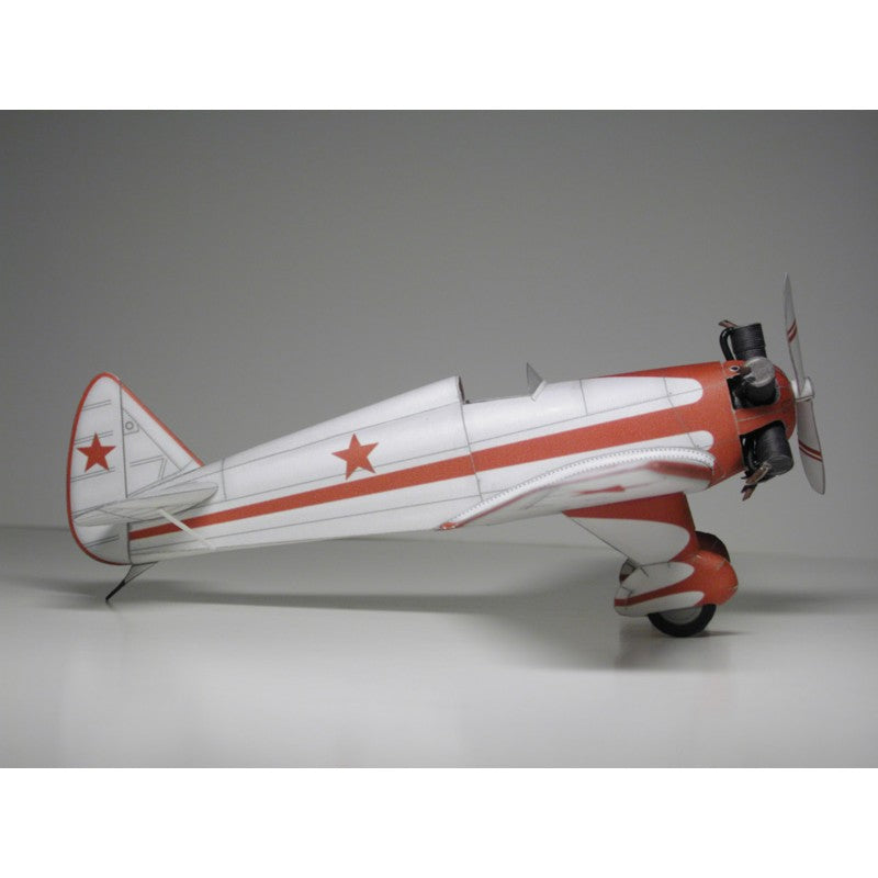 A scale model of a vintage twin-engine propeller airplane, featuring a white fuselage with bold red stripes and red star insignias, set against a neutral gray studio background.