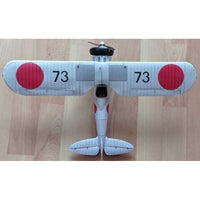 A small model airplane photographed from above on a light wood floor. The plane is white with two large red circular markings and the number 73 printed in black on each wing.