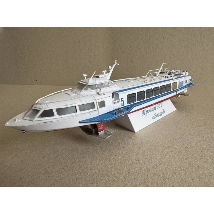 A white and blue model passenger ferry boat displayed on a small white stand against a plain beige background.