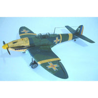 A model of a vintage military fighter plane, painted in a dark green and yellow camouflage scheme with Swedish cross insignias, shown against a light blue gradient background.