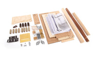 A flat-lay view of a miniature model kit components and accessories on a white background, including wooden rolling mats, small metal hardware, miniature figures, and a printed instruction booklet.