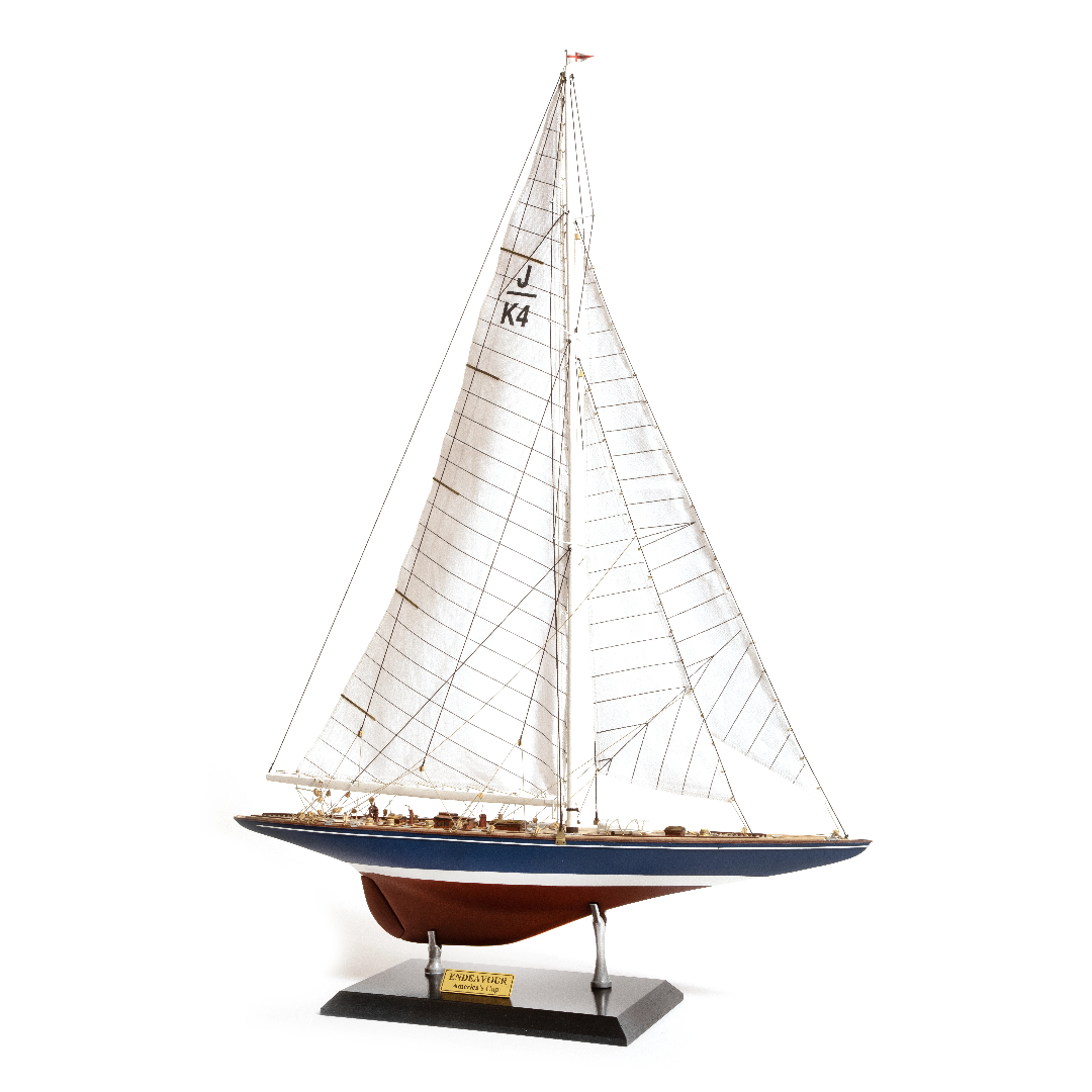 Photo of the OcCre Endeavour America's Cup yacht model kit in 1:75 scale, showing detailed wooden hull, rigging, and classic sail design.